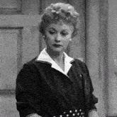 a black and white photo of a woman standing in front of a wooden door
