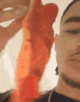 a man with a beard is holding a large orange object in his hand .