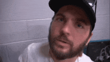 a man with a beard is wearing a hat and sunglasses and looking at the camera .