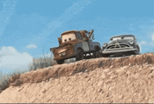a tow truck is pulling a car down a dirt hill