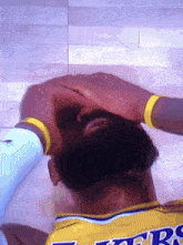 a man wearing a lakers jersey has his head on his hands