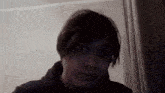 a man with short hair is making a funny face while looking at the camera in a dark room .