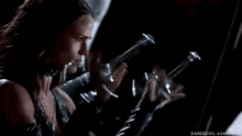 a woman in a leather outfit is holding a sword in her hand in a dark room .