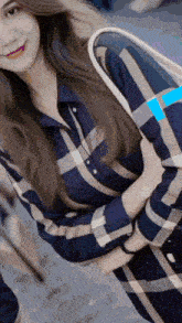 a woman wearing a plaid shirt is holding a bag