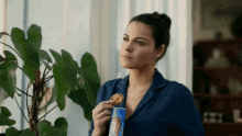 a woman in a blue shirt is eating a cookie from a can