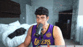 a man wearing a purple lakers jersey is speaking into a microphone