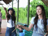 two women are standing next to each other on a porch holding a stick .
