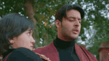 a man in a red jacket is standing next to a woman