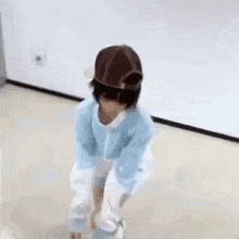 a person wearing a hat and a blue and white sweater is dancing on the floor .
