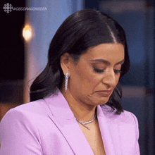 a woman wearing a purple suit and earrings is making a funny face .