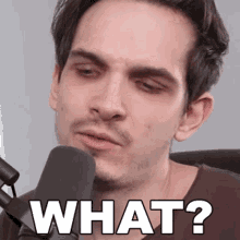 a man sitting in front of a microphone with the words what written on his face