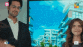 a man and a woman are standing in front of a screen that says hum hd on it