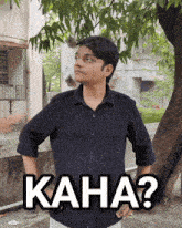 a man in a black shirt is standing in front of a tree with the words kaha written on the bottom