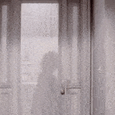a woman in a white dress is standing in a doorway holding a cup and a bottle .