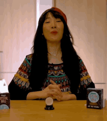 a woman sitting at a table with a crystal ball and a box that says crystal ball