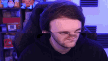 a man wearing glasses is sitting in a chair and making a face .
