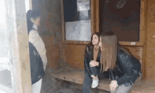 three girls are sitting on a wooden bench in a shelter .