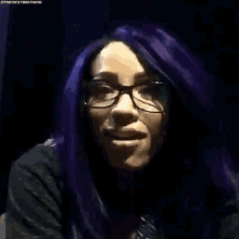 a woman with purple hair and glasses makes a funny face .