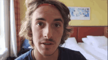 a young man with long hair and a headband on his head looks at the camera