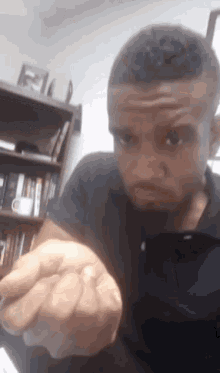 a man in a black shirt is making a funny face in front of a bookshelf