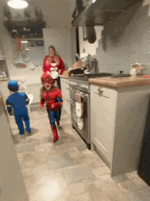 two children in spiderman costumes running in a kitchen