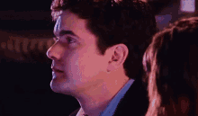 a close up of a man 's face with his eyes closed and a woman in the background .