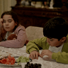 a boy and a girl sit at a table with food
