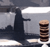 darth vader is standing next to a stack of cupcakes on a cake stand