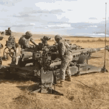 a group of soldiers are standing around a cannon in a field .