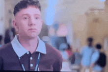 a man in a polo shirt with a lanyard around his neck is looking at the camera .