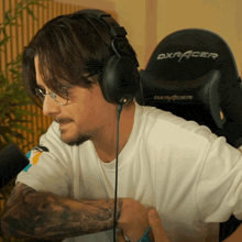 a man wearing headphones sits in a dxracer gaming chair