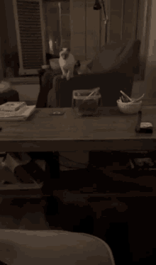 a blurred image of a person sitting at a table with a bowl of spoons on it