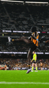 a man kicking a ball on a field with toyota advertisements in the background