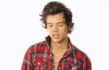 a young man wearing a plaid shirt and a necklace is making a funny face .