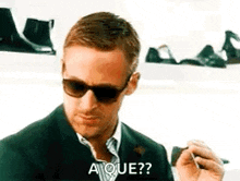 a man wearing sunglasses and a suit is smoking a cigarette and making a funny face .