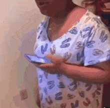 a woman wearing a blue and white shirt with the letters v and s on it holds a cell phone