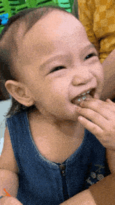 a little girl wearing a blue tank top with pineapples on it is smiling