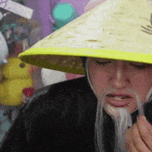 a person wearing a conical hat with a yellow stripe on the brim