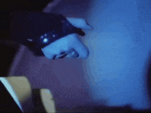 a close up of a person 's hand in a dark room with a blue light behind it