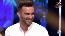 a man with a beard is smiling in front of a microphone on a tv show