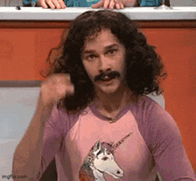 a man with long curly hair and a mustache is wearing a unicorn shirt .