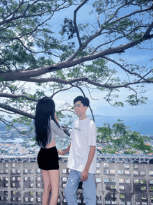 a boy and a girl are standing under a tree and the boy is wearing a white shirt that says abercrombie & fitch