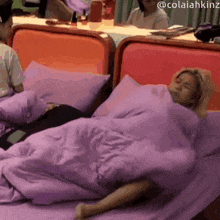 a woman is laying on a bed with a purple blanket and the name colaiahkinz on the bottom