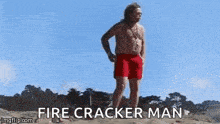 a man in a bathing suit is standing on a beach with a drone flying in the background .