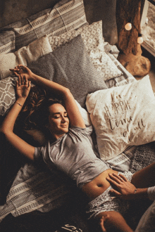 a woman is laying on a bed with a pillow that says " i 'm happier than all "