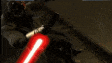 a man is fighting another man with a red light saber .