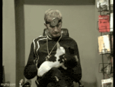a man wearing a stethoscope on his head holds a cat