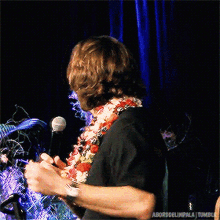 a man wearing a flower lei is holding a microphone and giving the middle finger