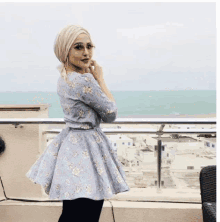 a woman in a floral dress is standing on a balcony