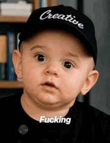 a baby wearing a hat that says creative fucking